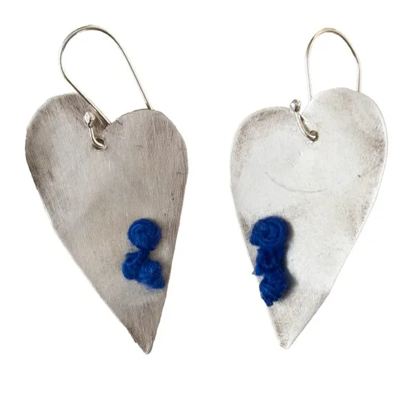 Handmade silver heart-shaped earrings, decorated with blue woolen details.